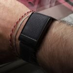 WHOOP wearable bandje op sportieve pols met herstel- en slaapstatistieken in de achtergrond