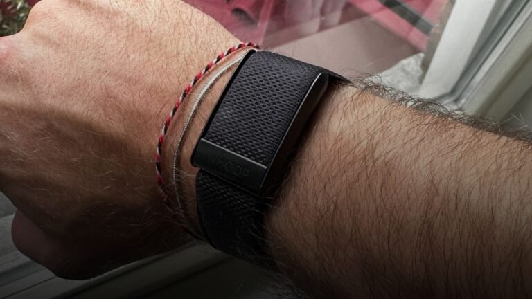 WHOOP wearable bandje op sportieve pols met herstel- en slaapstatistieken in de achtergrond