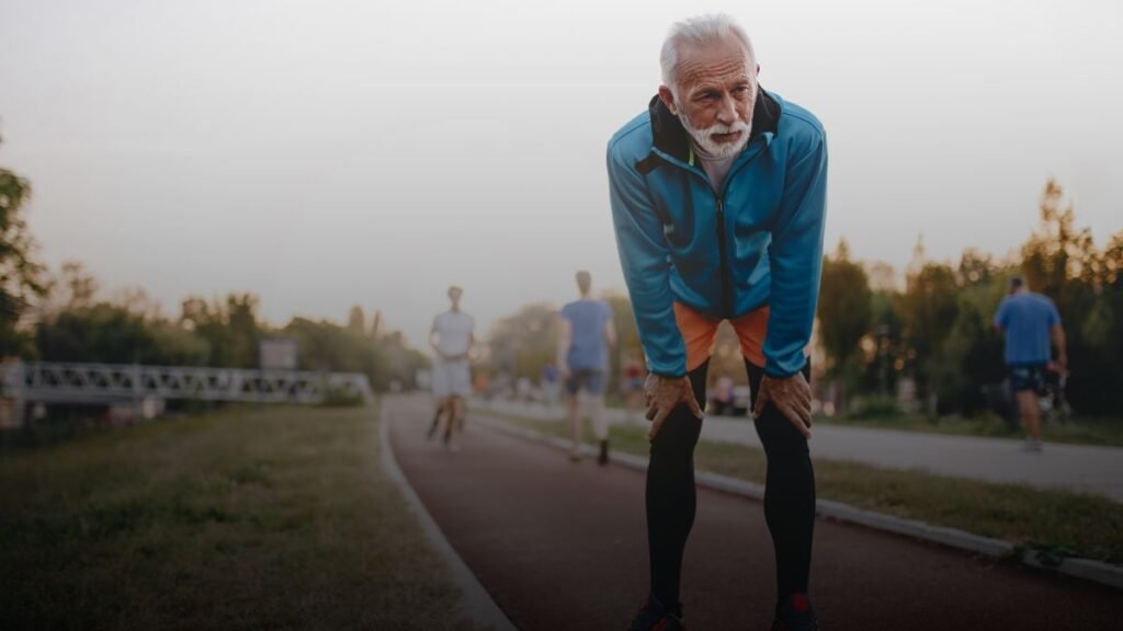 Oudere man staat gehurkt op baan na hardlopen