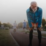 Oudere man staat gehurkt op baan na hardlopen