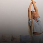 Iemand uitgerust strekken na power nap met bed op achtergrond